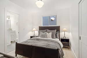 Bedroom with light wood-style flooring and ensuite bath