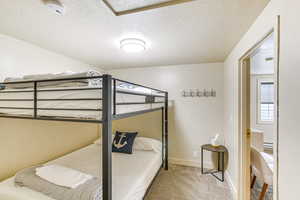 Bedroom with light colored carpet and a textured ceiling