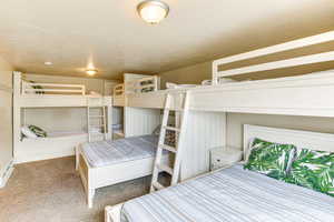 Bedroom with a textured ceiling, carpet, and baseboard heating