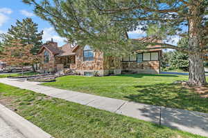 View of front of property with stone siding, a chimney, and a front lawn