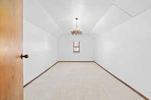 Additional living space with a chandelier, lofted ceiling, and carpet floors