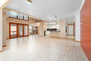 Unfurnished living room with light wood-style flooring and french doors