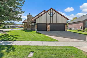 Tudor house featuring a front yard, board and batten siding, driveway, and a chimney