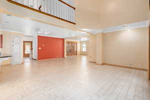 Unfurnished living room featuring ornamental molding, a towering ceiling, and light wood-style floors