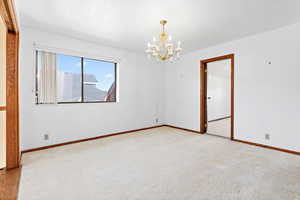 Unfurnished room with a chandelier and carpet
