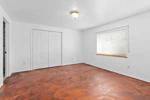 Unfurnished bedroom with a closet and concrete flooring