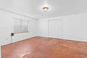Unfurnished bedroom featuring a closet and concrete floors