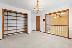 Spare room with a chandelier, light carpet, and ceiling fan