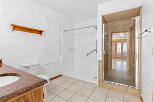 Full bathroom featuring light tile patterned floors, a stall shower, and vanity