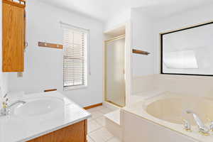 Bathroom featuring vanity, a garden tub, light tile patterned flooring, and a shower stall