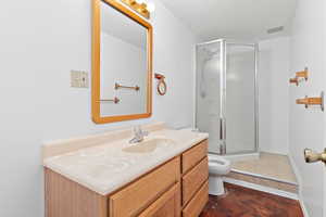 Full bath featuring vanity, a shower stall, and dark tile patterned flooring