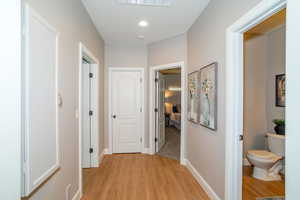 Hallway with light wood-style floors and recessed lighting