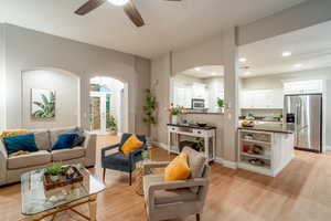 Living area featuring light wood-type flooring, ceiling fan, arched walkways, and recessed lighting