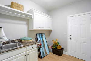 Laundry area with light wood-style floors and a sink