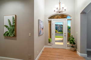 Entrance foyer with light wood-type flooring, a chandelier, and a textured wall