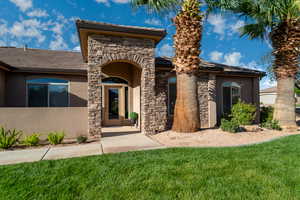 Mediterranean / spanish-style house featuring stone siding, stucco siding, and a front lawn