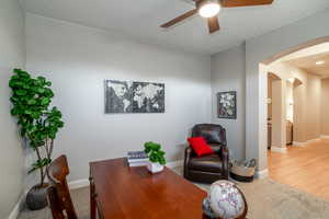Office area with arched walkways, light carpet, and ceiling fan