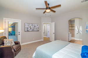 Bedroom with access to exterior, arched walkways, a ceiling fan, light carpet, and ensuite bathroom