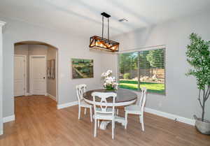 Dining area with arched walkways and light wood-style flooring