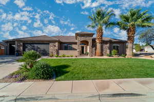 View of front facade featuring stone siding, a front yard, concrete driveway, and stucco siding