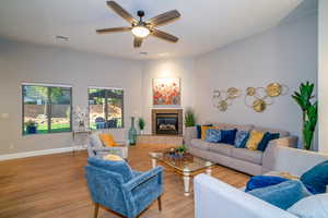Living area featuring wood finished floors, a ceiling fan, and a tiled fireplace