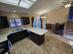 Kitchen featuring dark cabinetry, light countertops, a peninsula, electric range oven, and vaulted ceiling