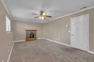 Unfurnished living room with ornamental molding, light colored carpet, a brick fireplace, and ceiling fan
