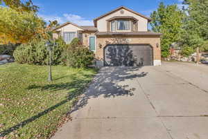 View of front of home with concrete driveway, brick siding, an attached garage, and a front yard