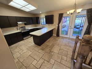 Kitchen featuring light countertops, french doors, electric stove, hanging light fixtures, and a peninsula