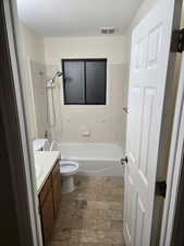 Bathroom featuring vanity, bathing tub / shower combination, stone tile floors, and a textured ceiling