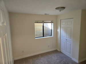 Unfurnished bedroom with dark carpet and a closet