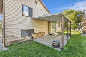 Back of house featuring a lawn, a patio, and entry steps