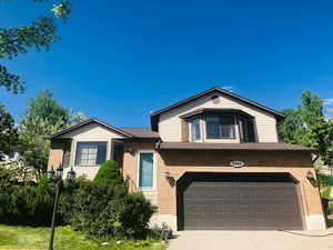 Split level home featuring brick siding, concrete driveway, and an attached garage