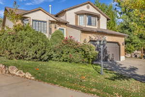 Traditional-style house featuring concrete driveway, a garage, brick siding, and a front yard