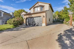 View of front facade featuring concrete driveway, brick siding, and an attached garage