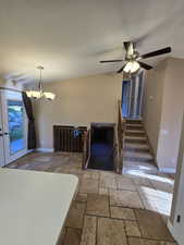 Foyer featuring stone tile flooring, a textured ceiling, a chandelier, lofted ceiling, and stairs