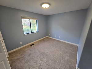 Spare room with carpet and baseboards