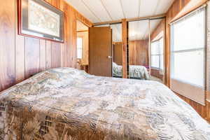 Bedroom with wooden walls and multiple windows