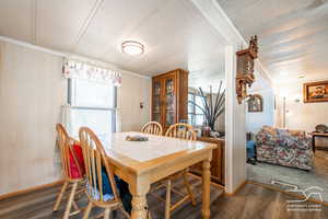 Dining room featuring dark wood finished floors, crown molding, a textured ceiling, and wood walls