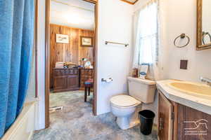 Bathroom featuring vanity, wood walls, and shower / bath combo with shower curtain