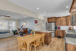 Kitchen with brown cabinetry, light stone counters, stainless steel appliances, decorative backsplash, and recessed lighting