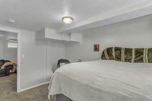 Carpeted bedroom featuring a textured ceiling and baseboards