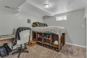 Carpeted bedroom featuring a textured ceiling and an office area