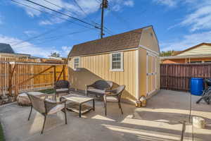 Fenced backyard with a storage unit and a patio