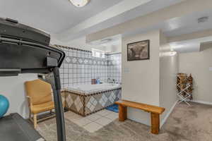 Exercise room with light tile patterned floors and light carpet