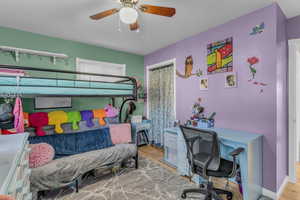 Bedroom with wood finished floors, ceiling fan, and a desk