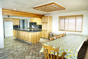 Kitchen with decorative backsplash, light brown cabinetry, freestanding refrigerator, a kitchen island, and brick flooring