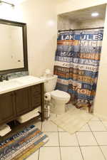 Full bathroom with vanity, light tile patterned floors, and a shower with curtain