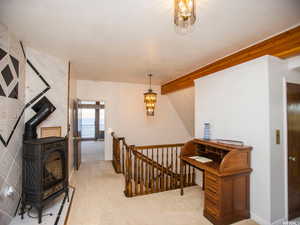Hall featuring an upstairs landing, light colored carpet, and a chandelier
