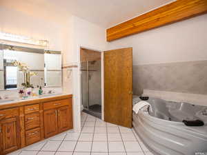 Full bathroom with double vanity, light tile patterned floors, a shower stall, a tub with jets, and tile walls